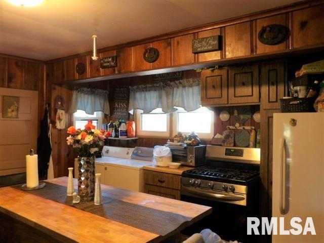 kitchen with brown cabinets, separate washer and dryer, stainless steel range with gas stovetop, and freestanding refrigerator