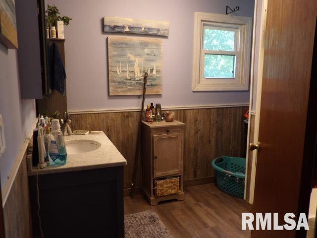 bathroom with a wainscoted wall, vanity, wood finished floors, and wood walls