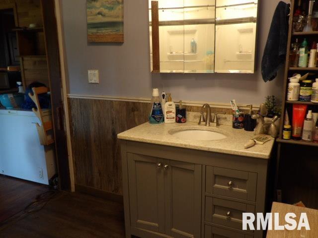 bathroom with a wainscoted wall, wooden walls, and vanity