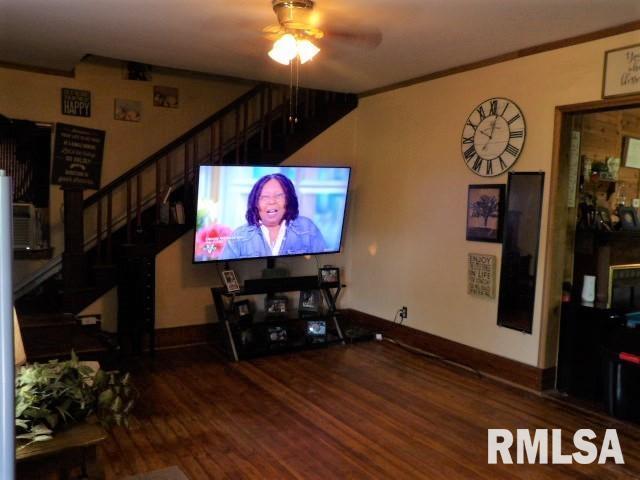 living room with crown molding, stairway, ceiling fan, wood finished floors, and baseboards