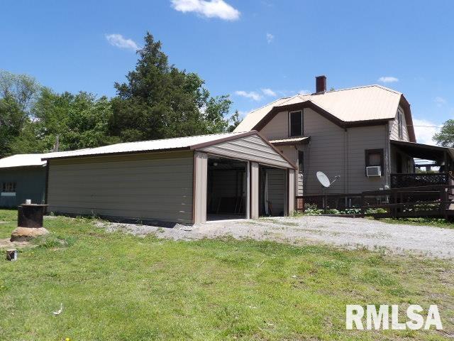 back of property featuring a garage, driveway, a lawn, and an outdoor structure