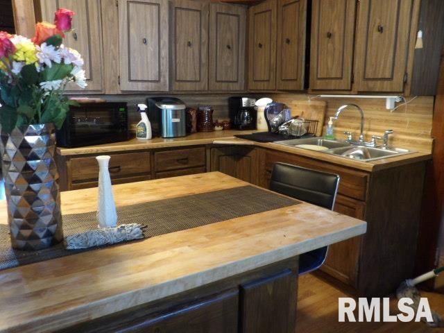 kitchen featuring decorative backsplash, wooden counters, and a sink