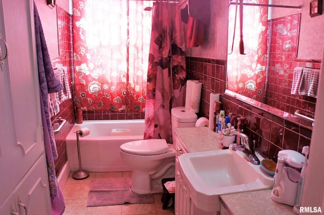 full bathroom featuring tile walls, toilet, a wainscoted wall, tile patterned flooring, and a sink