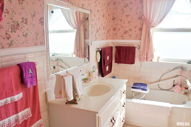 full bath featuring wallpapered walls, a garden tub, a wainscoted wall, and vanity