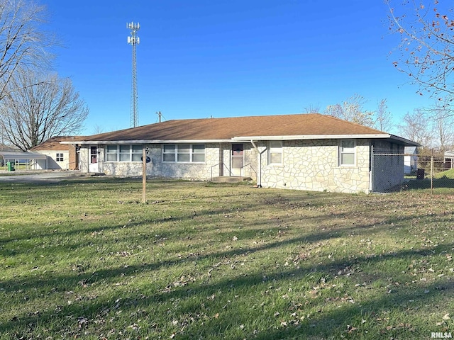 back of property featuring stone siding, fence, and a lawn