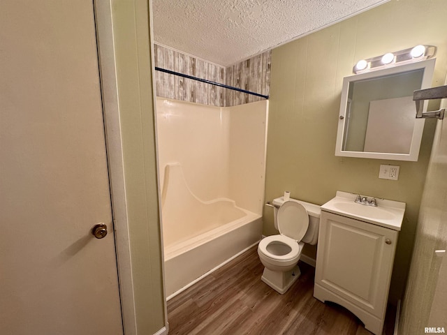 full bath with bathtub / shower combination, toilet, vanity, a textured ceiling, and wood finished floors