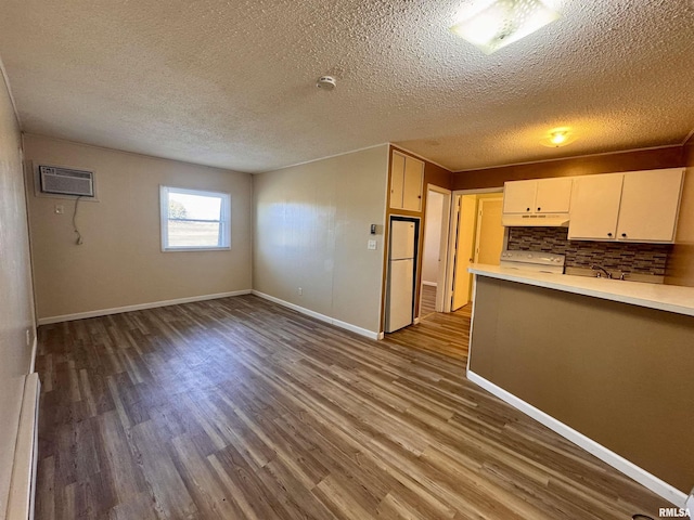 kitchen with a baseboard radiator, dark wood-style flooring, light countertops, a wall mounted AC, and decorative backsplash