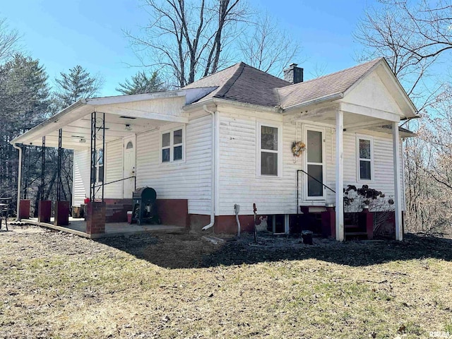 view of front of home with entry steps, roof with shingles, and a chimney