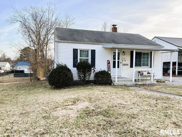 view of front facade with covered porch, a chimney, a front yard, and fence