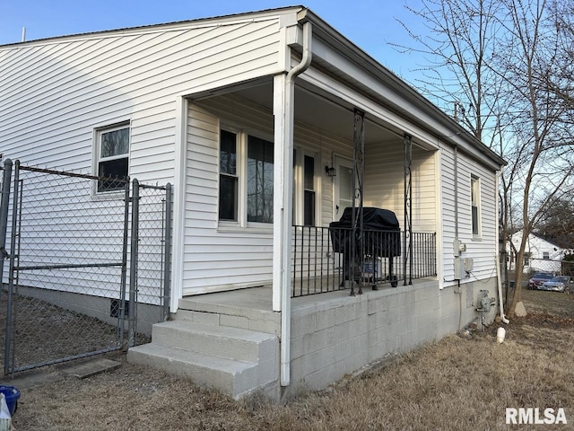 view of side of property featuring a gate, fence, and a porch