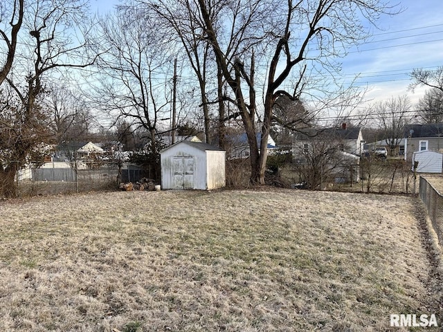 view of yard featuring a storage unit, an outdoor structure, and fence