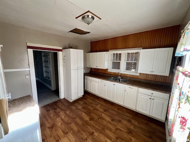 kitchen featuring dark countertops, a sink, dark wood finished floors, and white cabinets