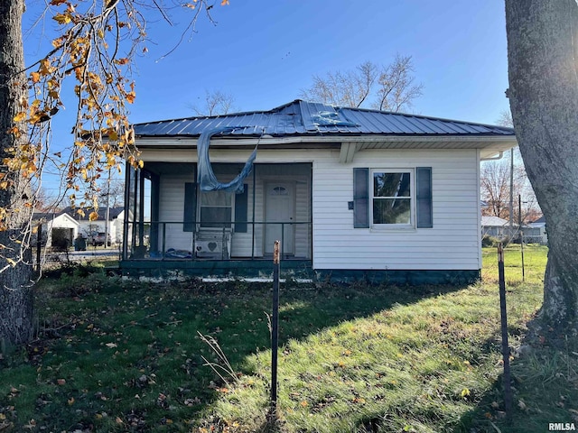 view of front of home with a front yard, covered porch, and metal roof