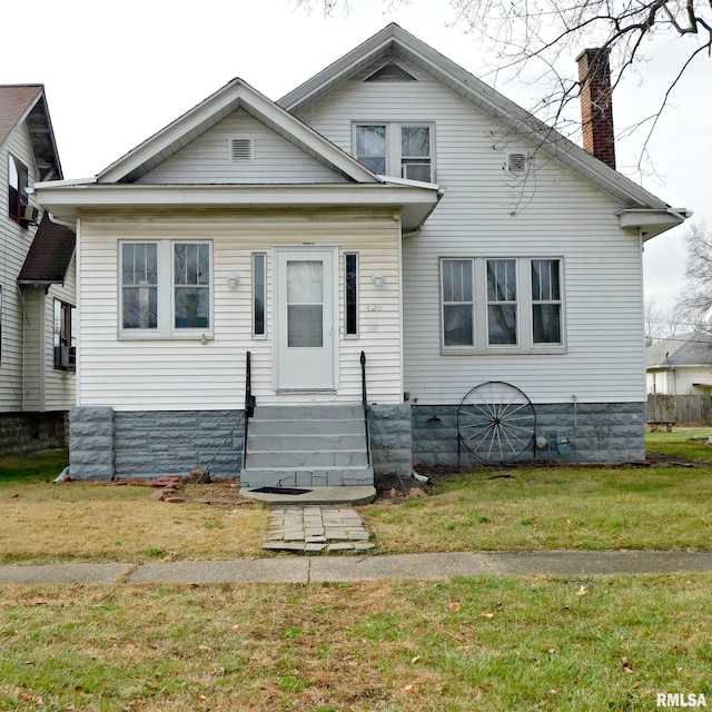 bungalow-style home with entry steps, a chimney, and a front lawn