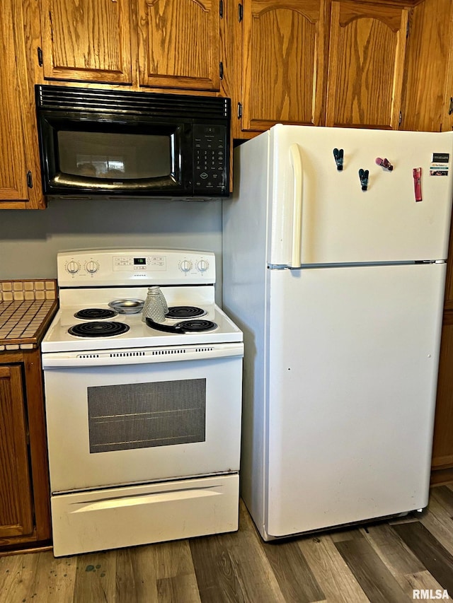 kitchen with white appliances, brown cabinets, and wood finished floors