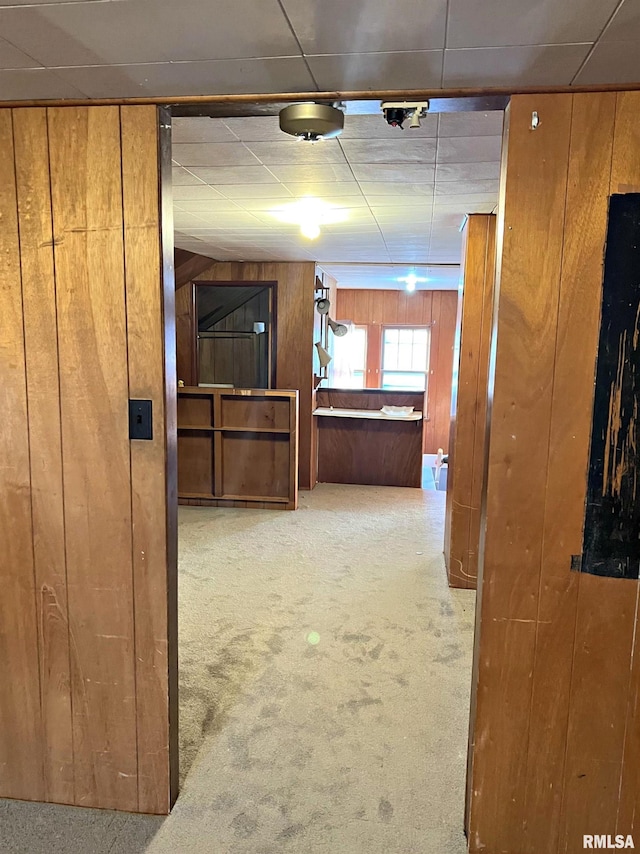 hallway featuring carpet floors and wood walls