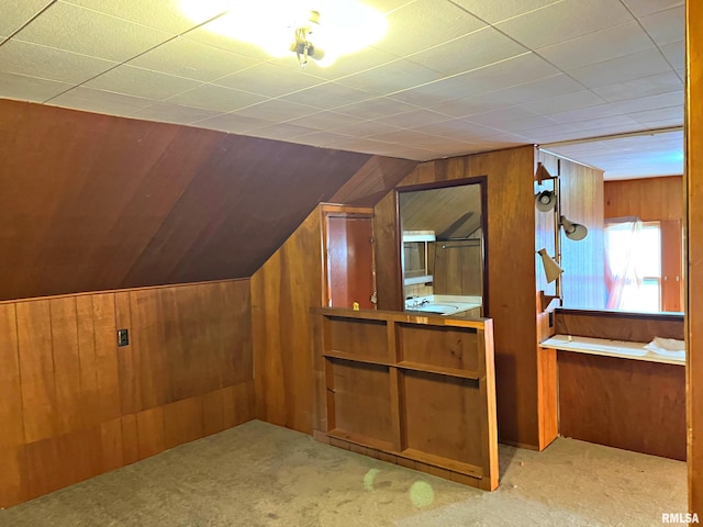 bonus room with lofted ceiling, wood walls, a sink, and carpet flooring