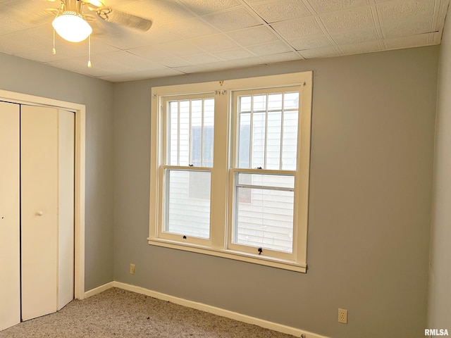 unfurnished bedroom featuring a ceiling fan, a closet, light colored carpet, and baseboards