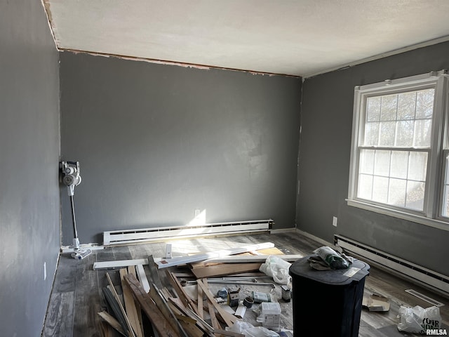 spare room with a baseboard radiator, baseboards, and wood finished floors