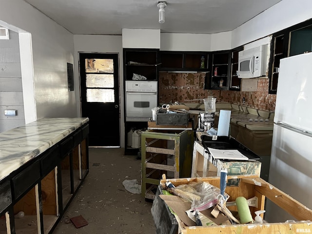 kitchen featuring white appliances, concrete floors, and dark cabinetry