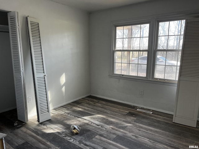 unfurnished bedroom featuring dark wood-style floors, visible vents, and baseboards