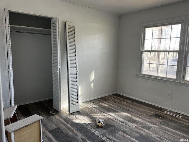 unfurnished bedroom featuring visible vents, a closet, baseboards, and wood finished floors