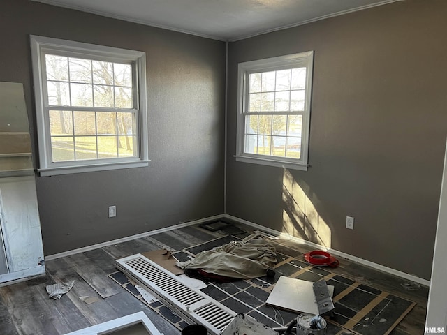 spare room with baseboards, wood finished floors, and a healthy amount of sunlight