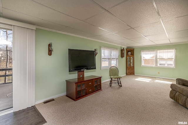 carpeted living area featuring visible vents, a paneled ceiling, and baseboards