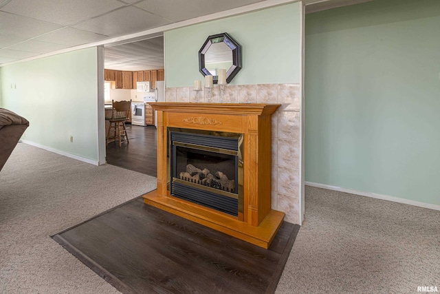 interior details featuring carpet floors, white electric range, a fireplace, and baseboards