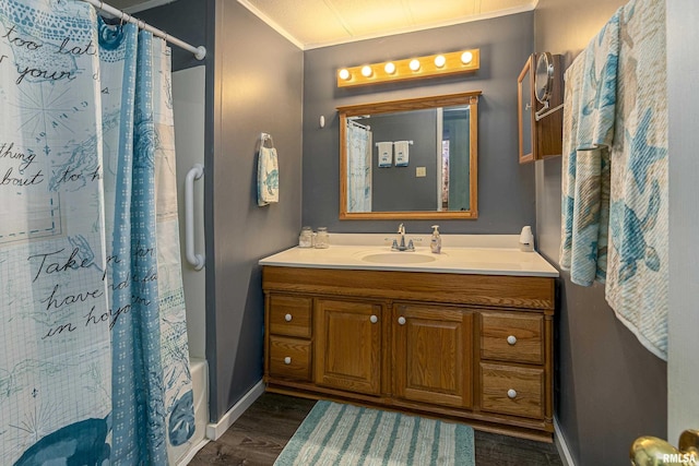 bathroom featuring crown molding, baseboards, wood finished floors, and vanity