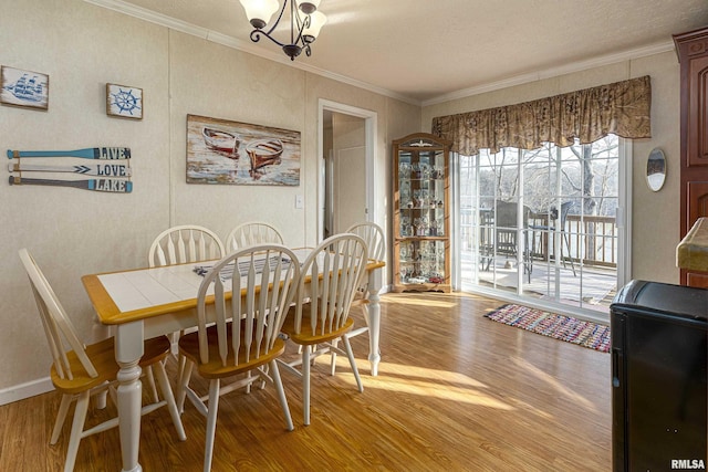 dining space with ornamental molding, a chandelier, baseboards, and wood finished floors