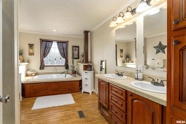 full bath with crown molding, a garden tub, a sink, and wood finished floors