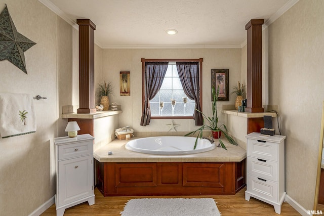 bathroom featuring a textured ceiling, wood finished floors, ornamental molding, a bath, and decorative columns