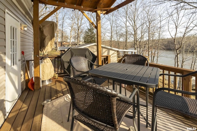 wooden terrace featuring outdoor dining space and a water view