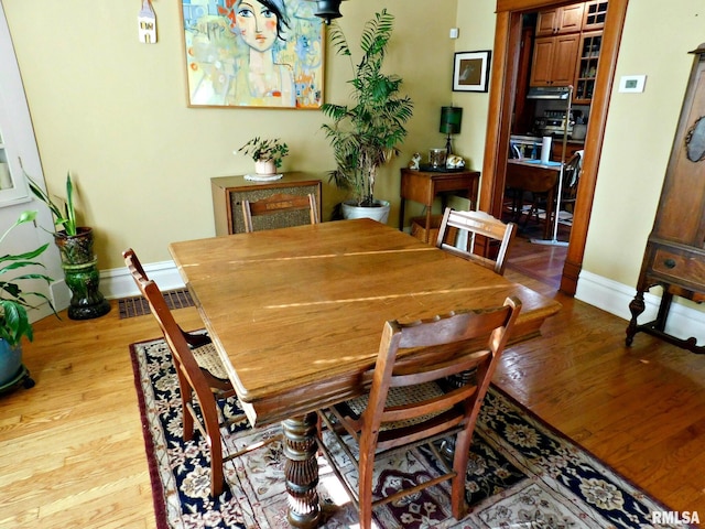 dining area featuring visible vents, baseboards, and wood finished floors