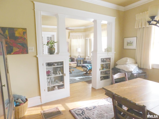 interior space featuring crown molding, light wood-style floors, and ornate columns