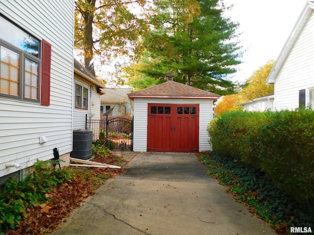 view of outbuilding with driveway, an outdoor structure, and a gate