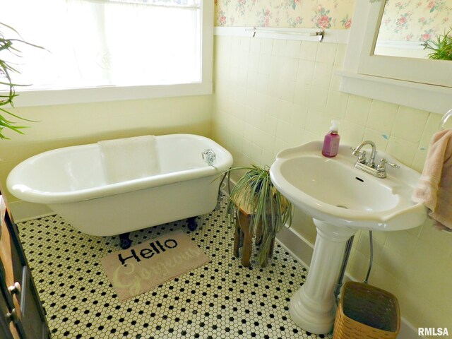 bathroom with tile patterned flooring, wainscoting, a freestanding bath, and wallpapered walls