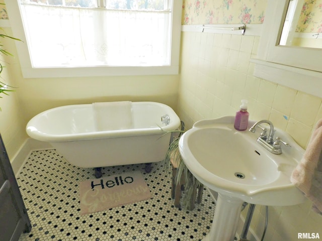 full bath featuring a wealth of natural light, a soaking tub, tile patterned flooring, and tile walls