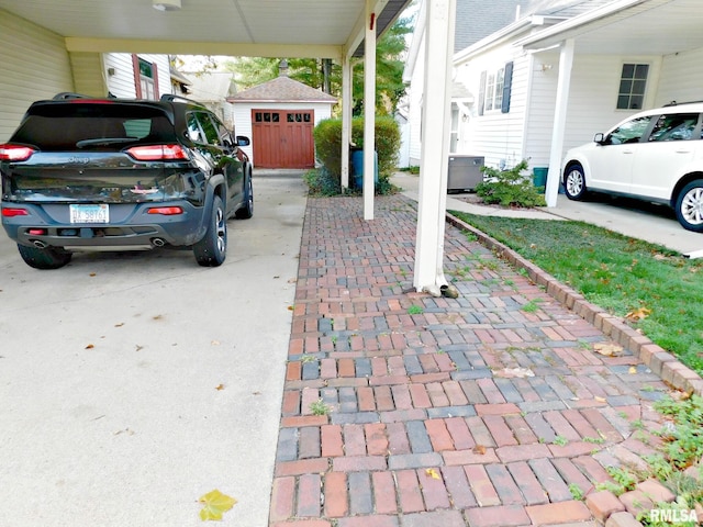 view of patio / terrace featuring driveway, a storage shed, a detached garage, and an outbuilding