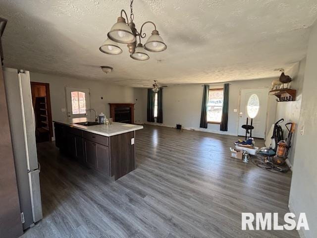 kitchen featuring a fireplace, light countertops, freestanding refrigerator, open floor plan, and a sink