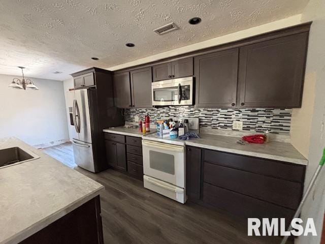 kitchen featuring dark wood finished floors, light countertops, visible vents, appliances with stainless steel finishes, and dark brown cabinets