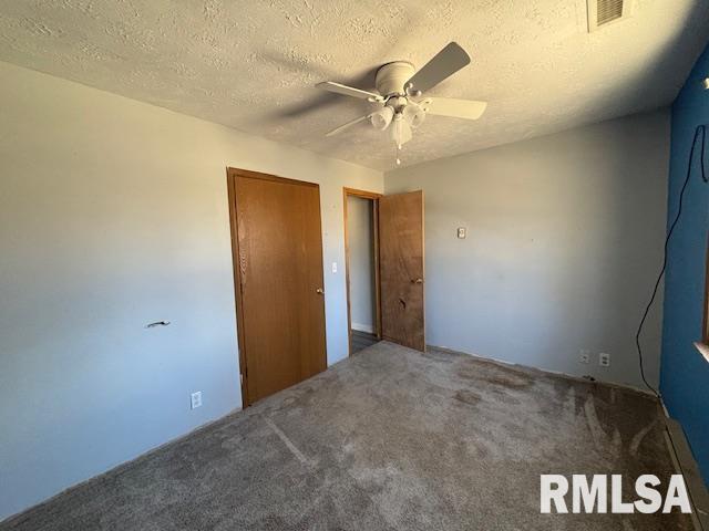 unfurnished bedroom with carpet, visible vents, ceiling fan, and a textured ceiling