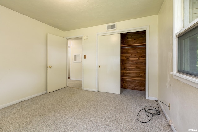 unfurnished bedroom featuring carpet floors, baseboards, visible vents, and a closet