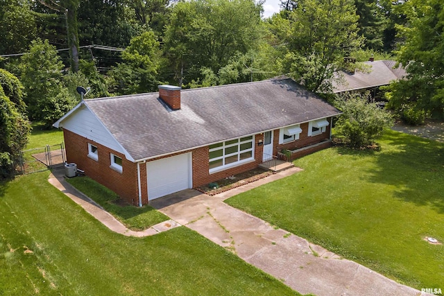 view of front of house featuring a garage, brick siding, concrete driveway, a chimney, and a front yard