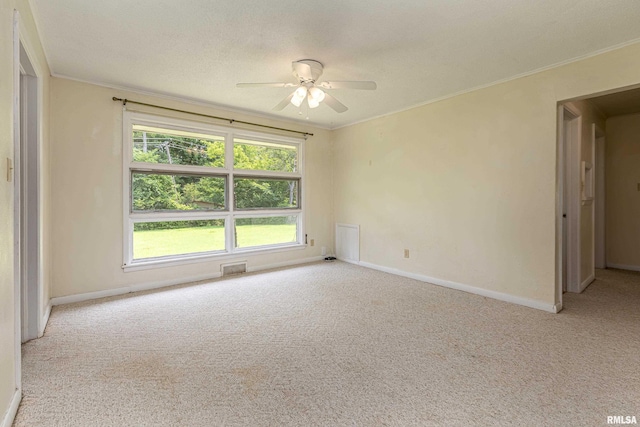 carpeted empty room featuring ornamental molding, visible vents, baseboards, and a ceiling fan