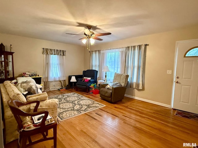 living area with ceiling fan, baseboards, and wood finished floors