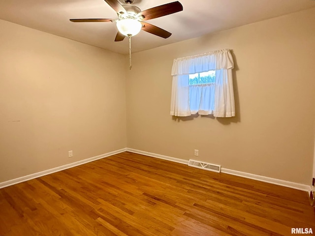 empty room featuring a ceiling fan, wood finished floors, visible vents, and baseboards