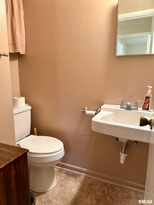 half bathroom with baseboards and toilet