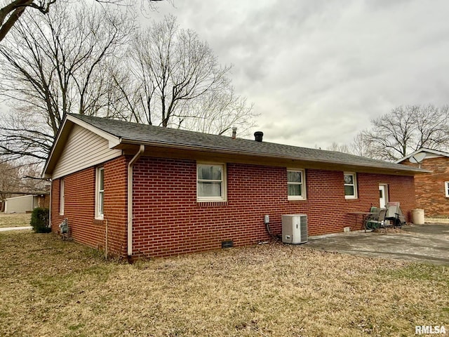 view of home's exterior featuring a patio, brick siding, a lawn, and central air condition unit